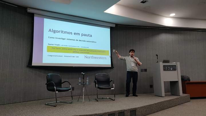 Daniel Trielli speaking and showing slides projected on a screen.